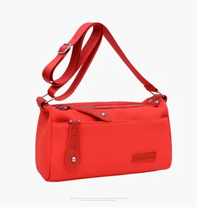Detail of red nylon shoulder bag featuring LB Luobolu leather logo and silver zippers
