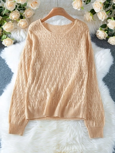 Détail du pull en maille crochetée abricot montrant les motifs de feuilles et la texture