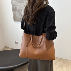 Large caramel leather tote bag with adjustable shoulder strap shown in a lifestyle view