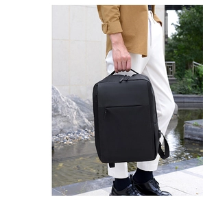 Business professional carrying a durable black laptop backpack in a modern outdoor park setting