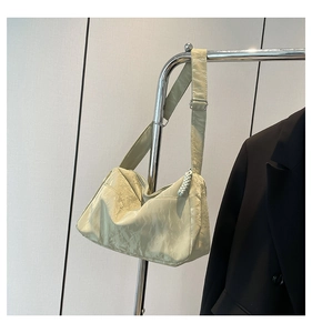 Close-up of light green pleated crossbody tote bag with adjustable shoulder strap and silver buckle