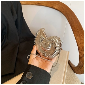 Detail of silver nautilus-shaped clutch bag with spiral texture and metal chain