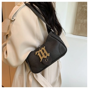 Détail du sac croissant noir vintage avec boucle dorée gothique porté sur un trench-coat