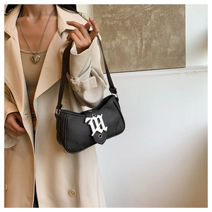 Détail du sac bandoulière en similicuir noir avec boucle gothique argentée W et fine sangle