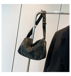 Detail of black wrinkled texture tote bag with adjustable strap and zip puller decoration