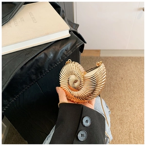 Detail of a golden nautilus shell clutch bag with metallic spiral texture and chain