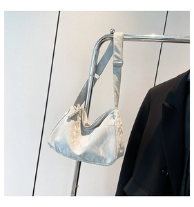 Detail of silver metallic hobo bag with knotted zipper and adjustable wide shoulder strap