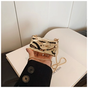 Detail of a mini gold chain bag with wrinkled metallic texture and fine snake bone chain