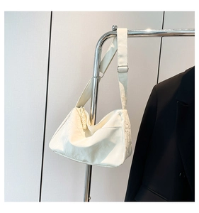Detail of cream nylon tote bag texture and adjustable strap hanging on a hanger