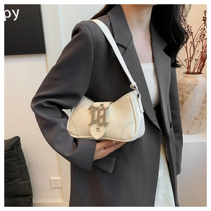 Vue détaillée du sac croissant crème avec boucle H gothique porté sur un blazer gris
