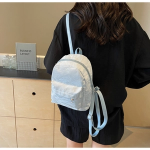 Close-up of light blue mini backpack with unique crinkled texture and sleek front pocket