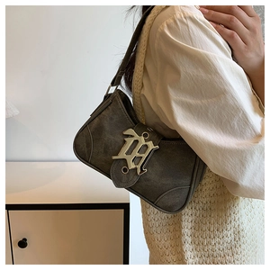 Détail d'un sac baguette en denim délavé avec une boucle H métallique au style gothique