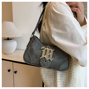 Détail du sac croissant en denim gris avec boucle M dorée porté en sac à bandoulière