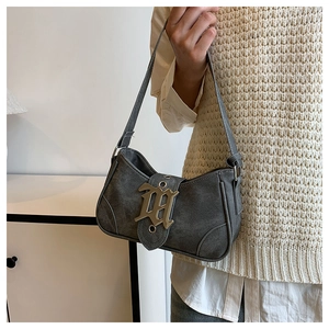 Détail du sac à bandoulière en denim gris avec boucle gothique sur le mannequin