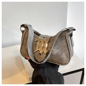 Détail macro du denim gris et de la boucle dorée gothique M sur le sac en croissant