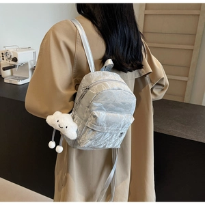 Detail of silver metallic wrinkled backpack with cute cloud plush charm on model
