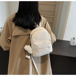Detailed view of beige backpack with jacquard texture and cute white cloud keychain
