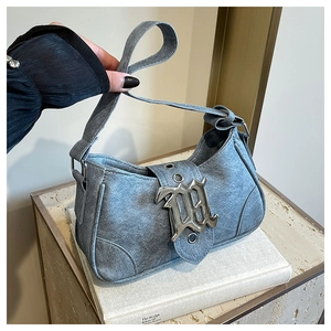 Gros plan d'un sac demi-lune gris rétro avec une grande boucle gothique sur des livres