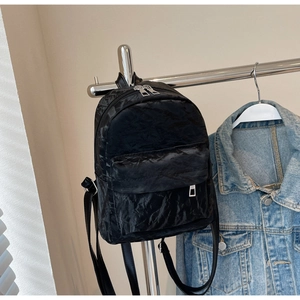 Detail of black mini backpack with textured fabric and dual zipper compartments
