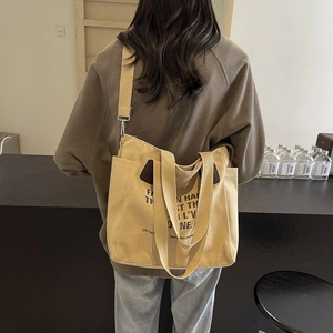 Grand sac cabas en toile beige avec imprimé noir dans un décor de café minimaliste