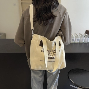 Sac fourre-tout minimaliste en toile blanc cassé avec lettrage noir et large bandoulière