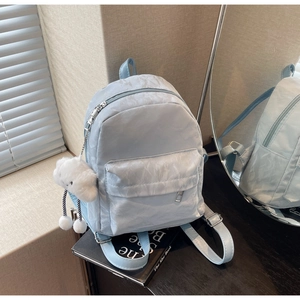 Detail of light blue nylon backpack featuring wrinkled texture and white cloud plush charm