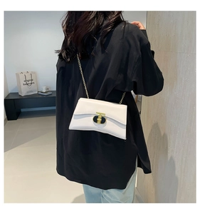 Détail du sac carré crème avec bandoulière chaîne dorée et boucle élégante