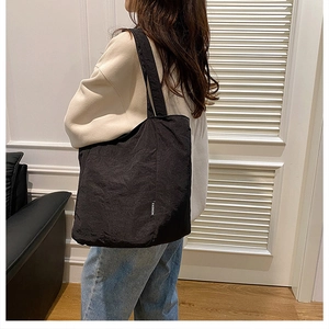 Détail du sac cabas noir avec texture de tissu froissé et étiquette Fashion discrète