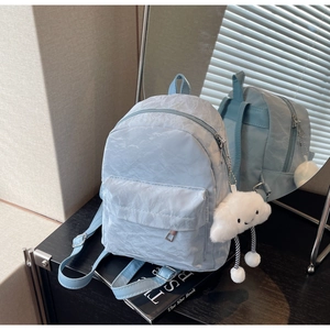 Detail of light blue crinkled nylon mini backpack with a white plush cloud charm accessory