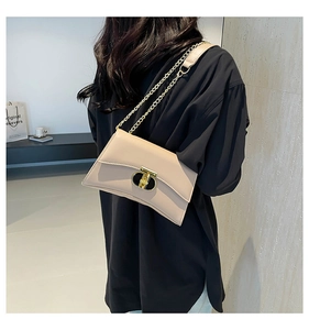 Modèle portant un petit sac carré beige avec bandoulière chaîne et fermoir doré chic