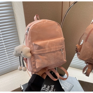 Detail of light pink mini backpack with pleated texture and white cloud plush charm