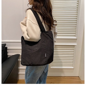 Détail du sac fourre-tout plissé noir minimaliste avec étiquette FASHION sur la bandoulière