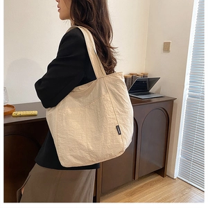 Détail d'un grand sac fourre-tout beige en toile avec étiquette et poche frontale