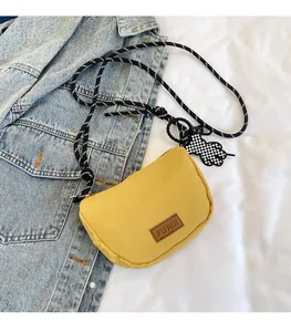 Dettaglio della borsa a mezzaluna in tela gialla con tracolla intrecciata e logo