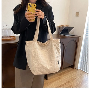 Détail du cabas beige montrant le tissu plissé texturé et l'étiquette FASHION