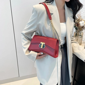 Sac bandoulière bordeaux minimaliste avec chaîne et boucle émail sur blazer crème