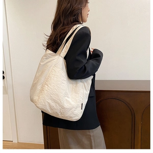 Détail du sac cabas beige montrant la texture en nylon lavé et l'étiquette latérale