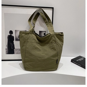 Détail du sac cabas en nylon vert armée avec doubles poches avant et texture froissée