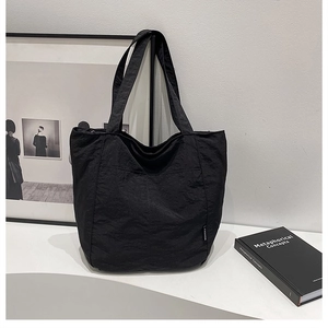Détail d'un grand sac fourre-tout en nylon noir avec poche avant et étiquette FASHION