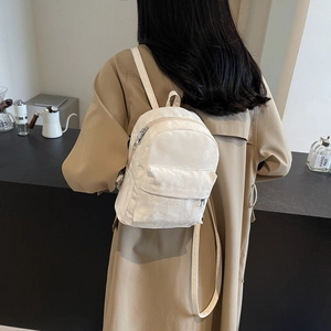 Minimalist white pleated backpack for women in a stylish cafe setting with straps