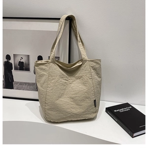 Détail du sac cabas beige avec texture plissée et étiquette de mode élégante