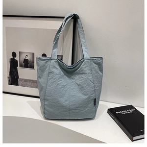 Détail du tissu plissé bleu clair du sac fourre-tout avec étiquette noire minimaliste