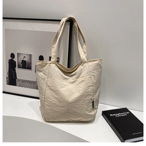 Gros plan d'un sac cabas beige montrant la texture en nylon et l'étiquette Fashion tendance
