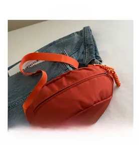 Detail view of orange crescent waist bag with durable nylon fabric and woven zipper puller