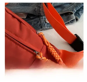 Close-up of orange outdoor fanny pack showing smooth metal zipper with woven pull cord