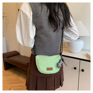 Borsa a tracolla verde menta con tracolla intrecciata e ciondolo a forma di orso