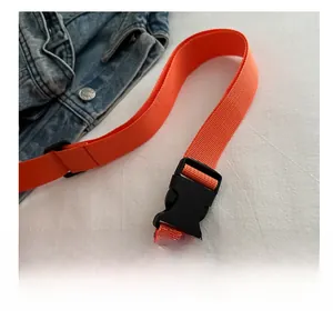Detail of durable black plastic buckle on bright orange nylon strap for casual crossbody bag