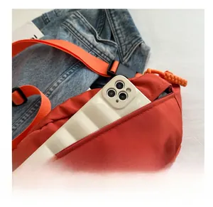 Detail view of orange nylon crossbody bag showing the zipper pocket and interior capacity