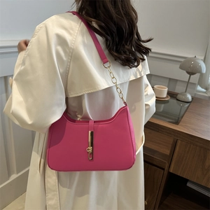 Rose pink crescent underarm bag with adjustable strap and gold chain detail on model