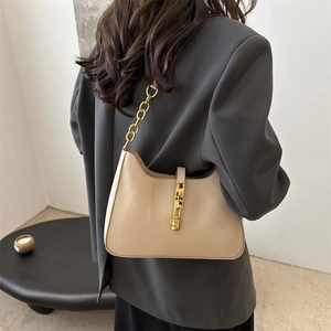 Beige crescent underarm bag with gold chain strap and metal clasp shown on model